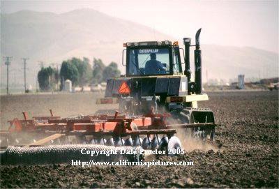 scenes in farm field farmer cultivates land turning soil, rotating crops in photo view of tractor Camarillo, California